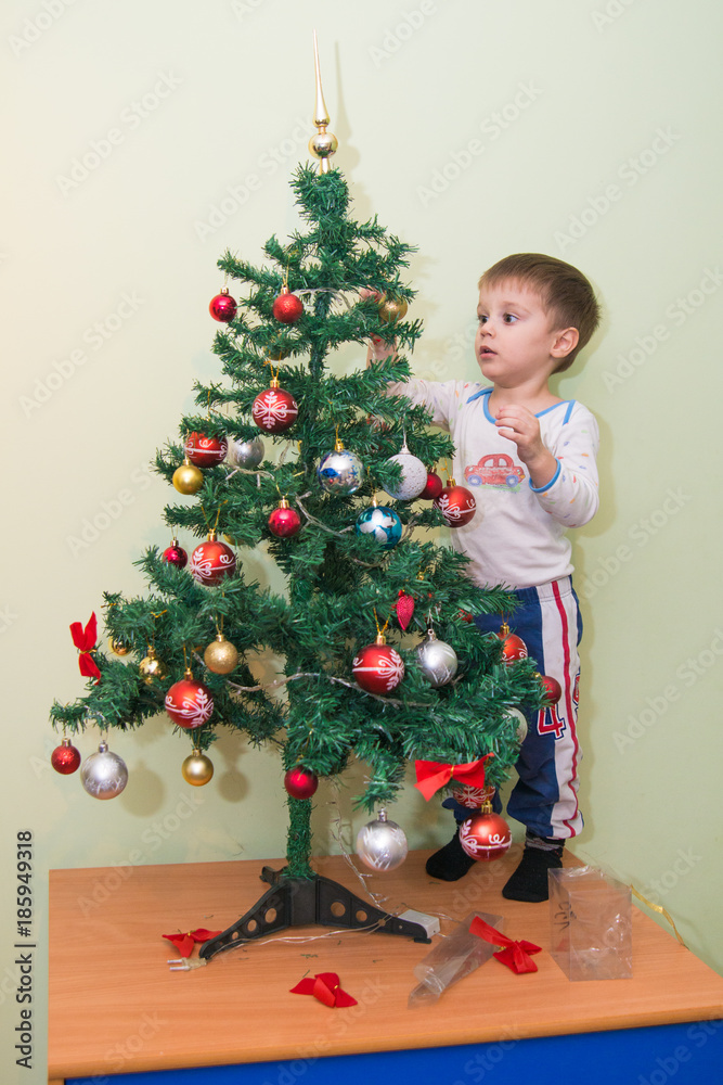 The boy decorates the New Year's tree