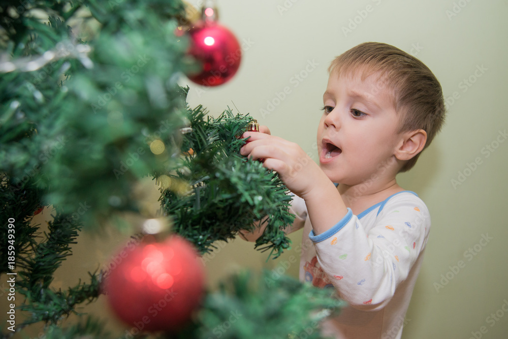 The boy decorates the New Year's tree