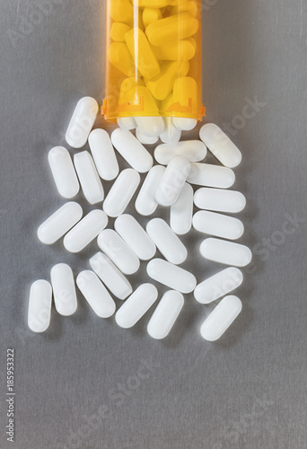 фотографія Opioid tablets spilling out of bottle onto stainless steel table