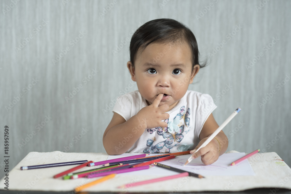 asian toddler / baby girl is having fun learning to use pencils. Education concept. human growth concept. asian toddler / baby girl is having fun learning to use pencils. Education concept. human growth concept.