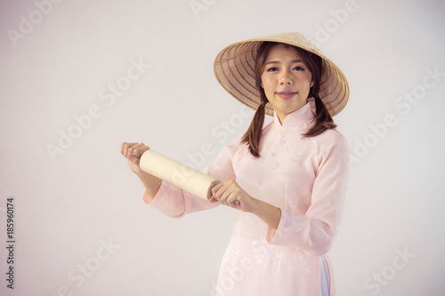 beautiful woman in pink dress and vietnam hat holding rolling pin. photo