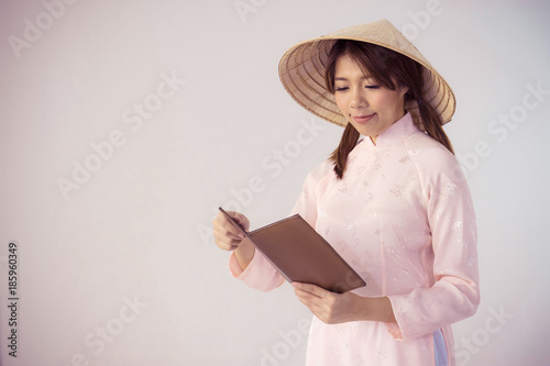 beautiful woman in pink dress and vietnam hat holding book photo