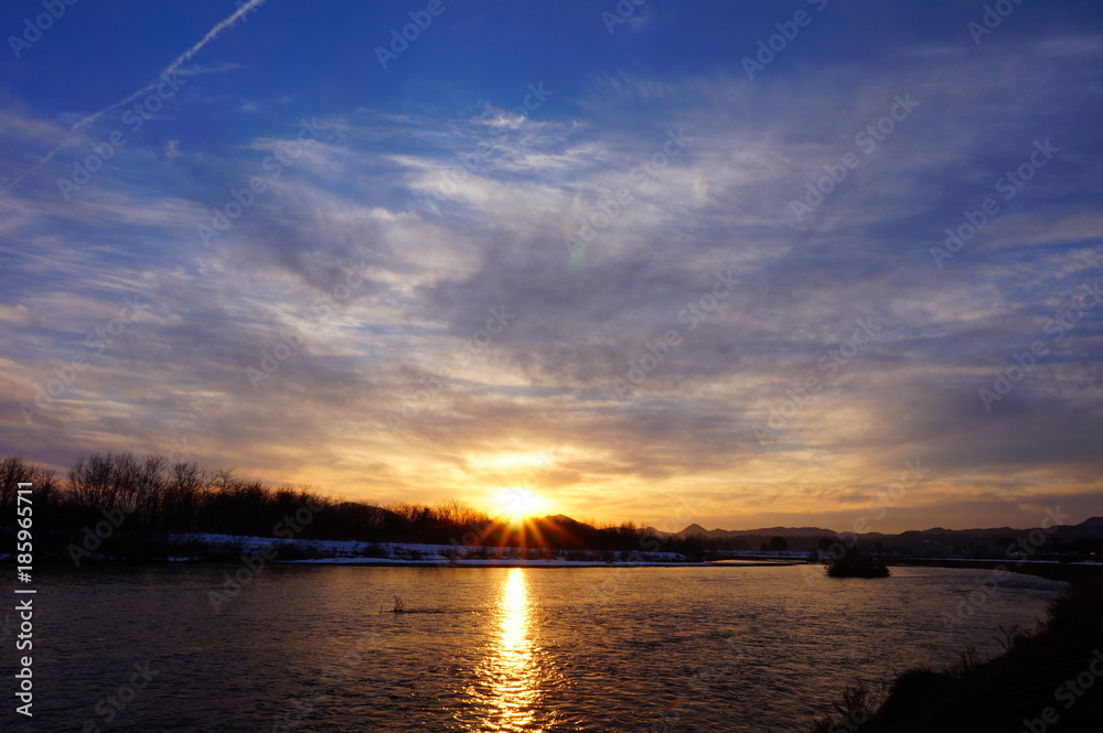 川の日没　青空　太陽の光芒