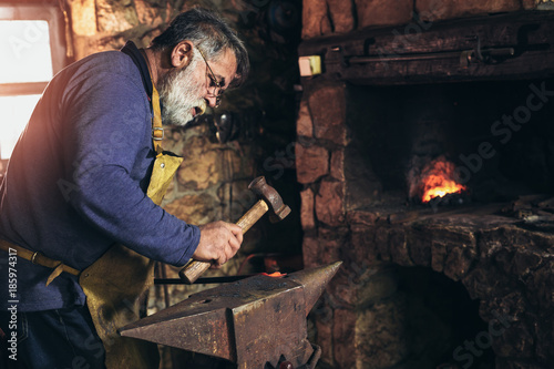 Senior blacksmith forge iron at work