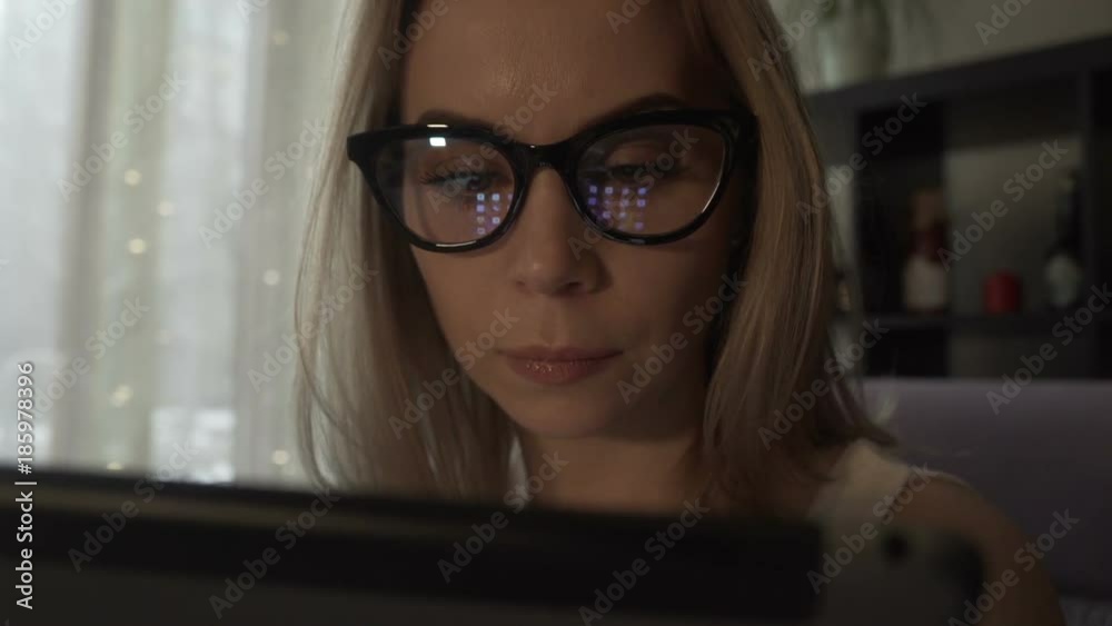 Beautiful woman using modern tablet pc and screen reflecting in glasses