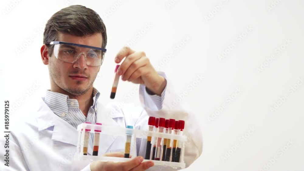 The doctor is in the laboratory. He wore special transparent glasses. He picks up a test tube with blood for medical tests. The doctor carefully studies it The doctor is in the laboratory. He wore special transparent glasses. He picks up a test tube with blood for medical tests. The doctor carefully studies it