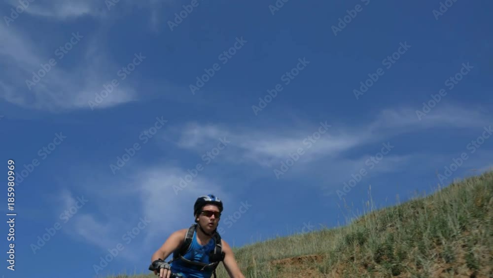 Fat bike also called fatbike or fat-tire bike in summer driving on the road. The guy rides by the hill on a sand clay path, behind him the shore by the sea. Slow motion shooting 180fps. Fat bike also called fatbike or fat-tire bike in summer driving on the road. The guy rides by the hill on a sand clay path, behind him the shore by the sea. Slow motion shooting 180fps.