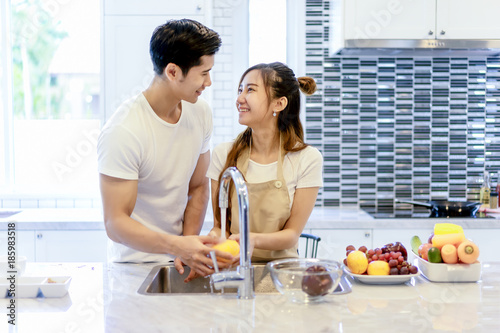 Beautiful asian young couple is looking to cooking in kitchen at home,Happy young woman washing vegetables.