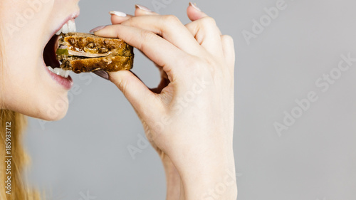 Woman eating sandwich, taking bite photo