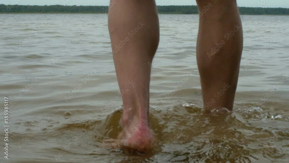 Mans legs going in the water slow motion Mans legs going in the water slow motion