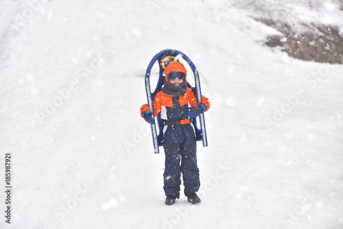 Little boy riding on snow slides in winter time