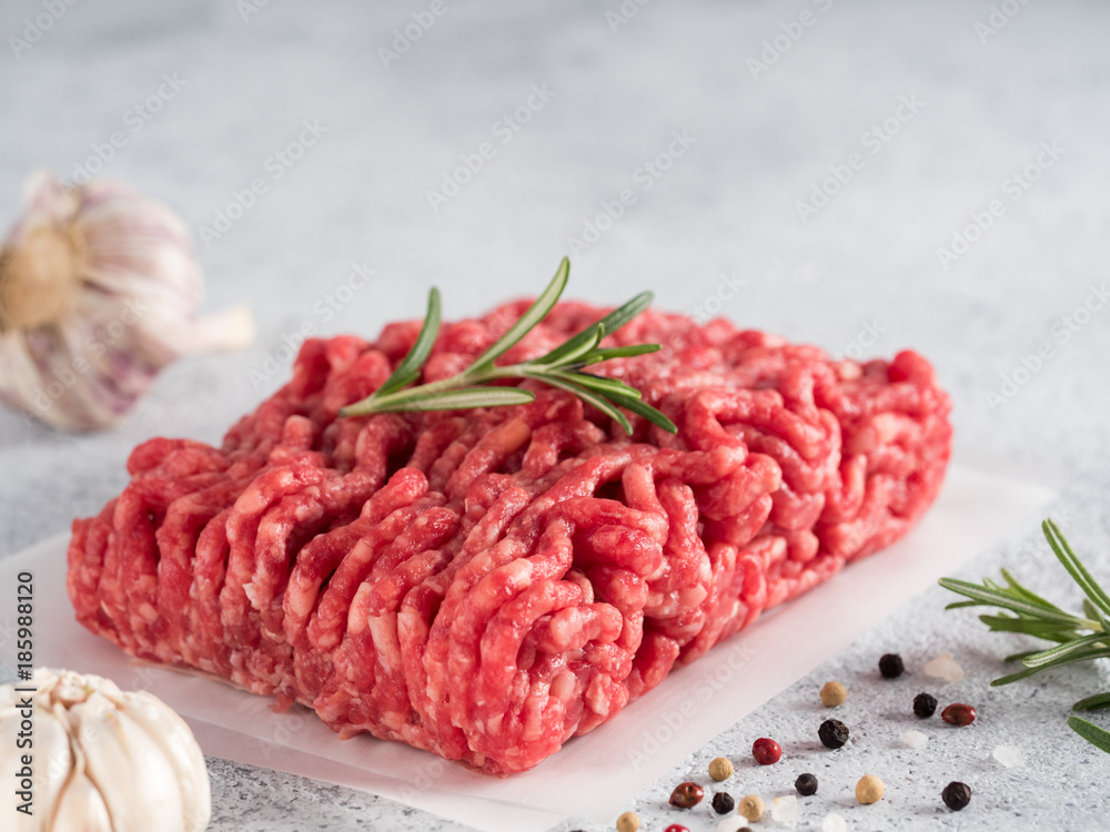 Fresh raw minced beef on backing paper over light gray cement background with copy space. Fresh raw minced beef on backing paper over light gray cement background with copy space.