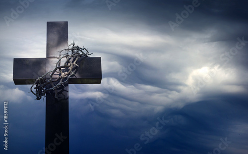 Easter cross with crown of thorns against blue sky abstract background with empty space 