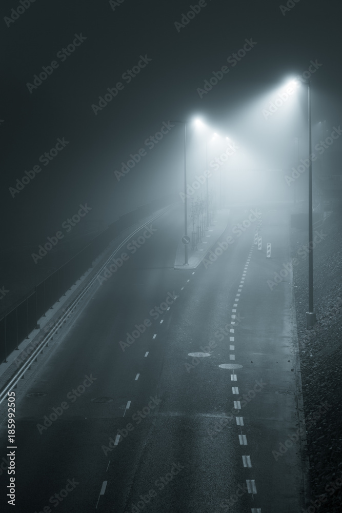 Empty road and streetlights at foggy night