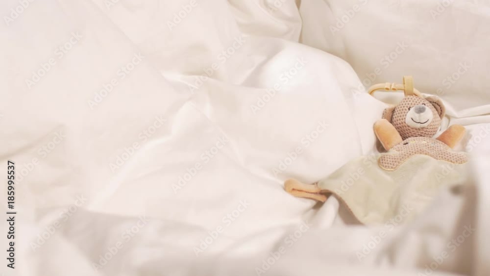 Baby toy in white bedsheets - close up Baby toy in white bedsheets - close up