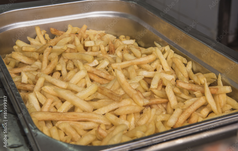 Tray of cooked French fries in silver serving dish