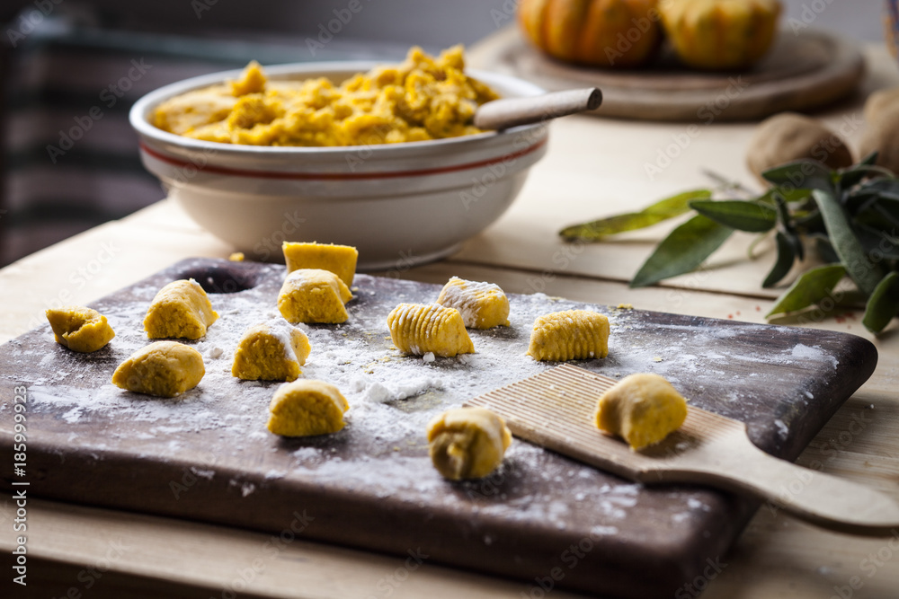 Preparing pumpkin gnocchi, rolling on wooden board Preparing pumpkin gnocchi, rolling on wooden board