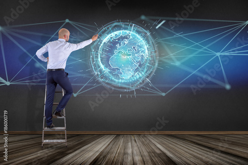 Businessman in front of a wall with connected earth globe concept icon on a futuristic interface