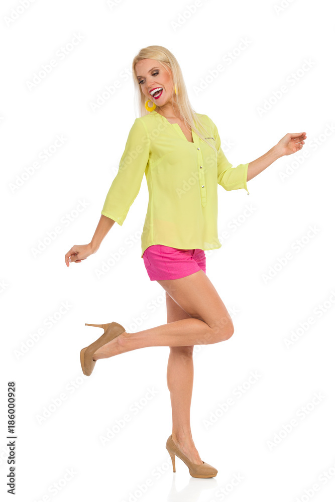 Carefree Woman In Vibrant Clothes And High Heels Is Danding On One Leg Carefree Woman In Vibrant Clothes And High Heels Is Danding On One Leg