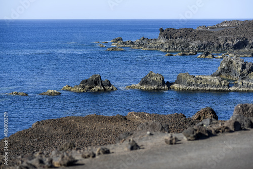 Volcanic rocks protruding from the assessment at the coast of the island of Lanzarote