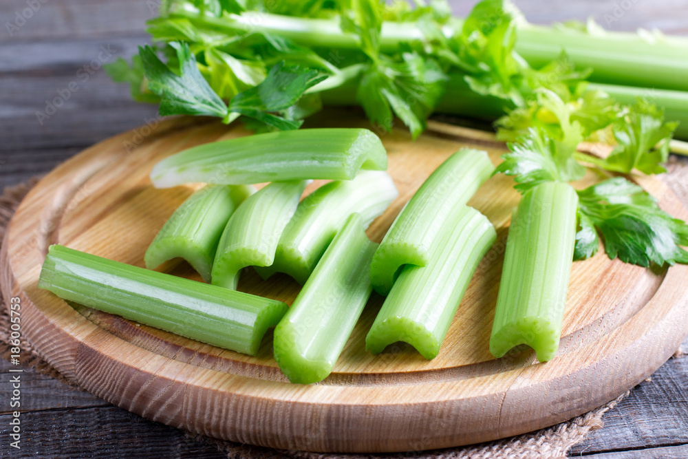 Fresh celery stems on wooden cutting board Fresh celery stems on wooden cutting board