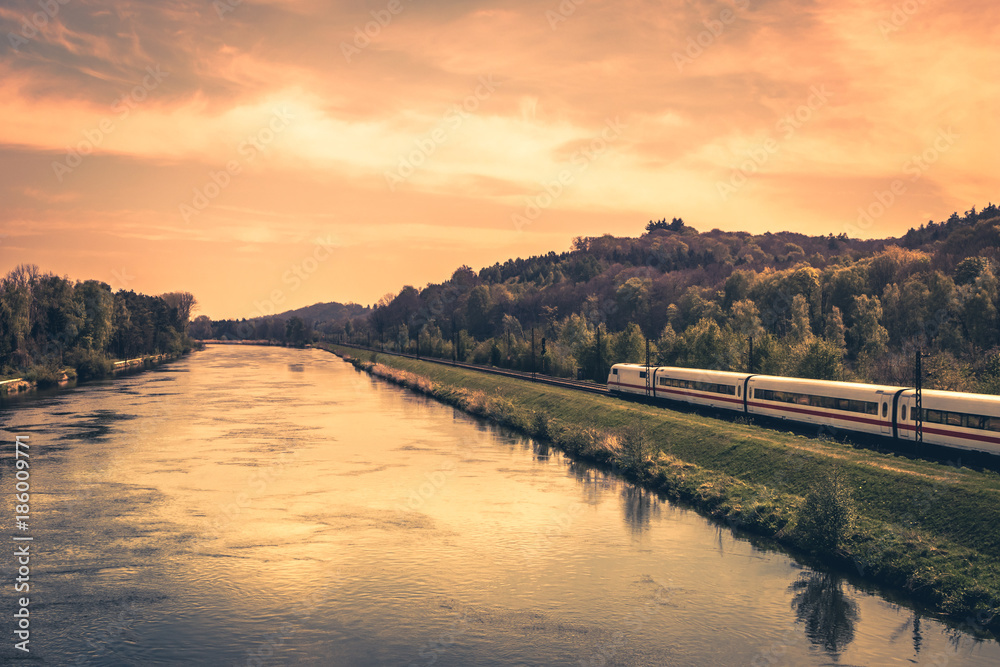 High-speed train on the bank of a river in evening sunset