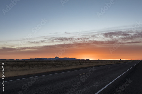 A lonely road passing by mountains during a cloudy sunrise