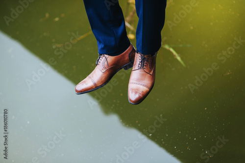 Legs and boots of a young man over the lake with reflection photo