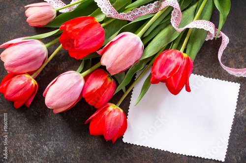 Valentine background or greeting card. Congratulatory sheet of paper with red and пинк tulips on a dark stone background. Free space for your congratulations.