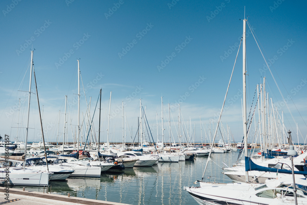 Yacht parking in harbor, harbor yacht club in Marina di Scarlino, Italy. Beautiful Yachts in blue sky background