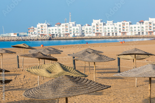 Fototapeta Naklejka Na Ścianę i Meble -  Beach loungers and umbrellas on the sea. Main beach in Agadir city located on the shore of the Atlantic Ocean.Morocco.
