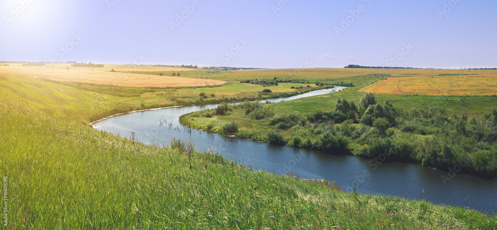 Sunny summer landscape with river.Green hills and meadows.Fields of ripe wheat.