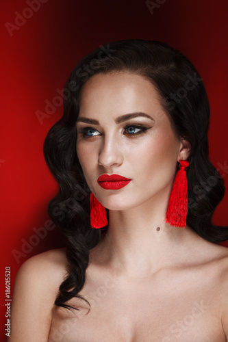 Glamour Portrait of Beautiful brunette Woman Model with Evening Make-Up and Hollywood Hairstyle at Red Background photo