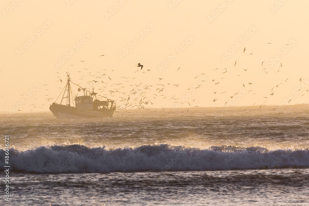 Fishing boat with sunset in the background at Essaouira, Morocco.
