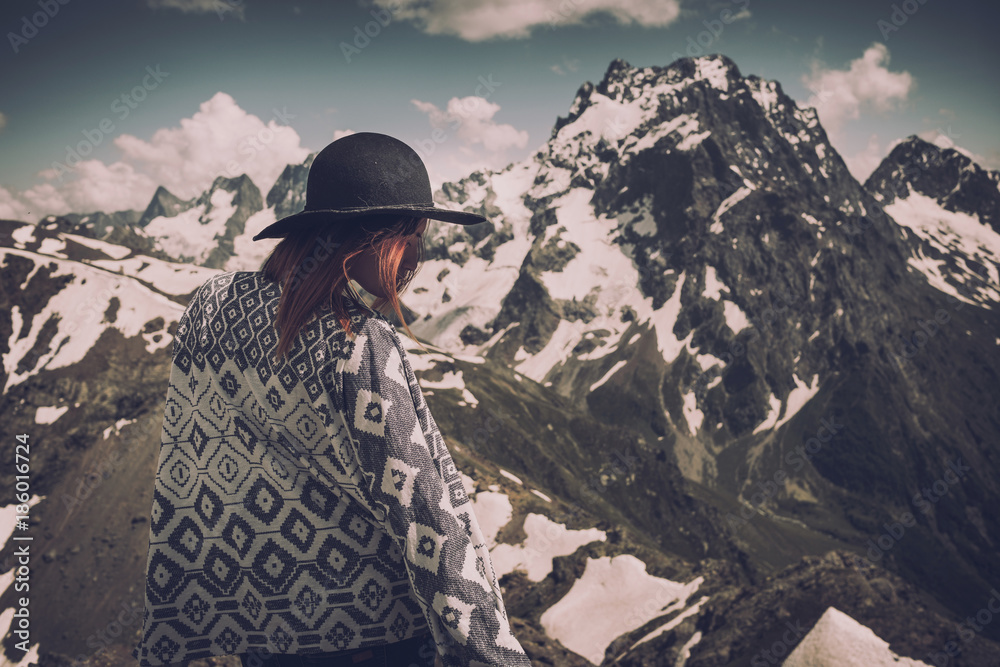 Boho woman wearing hat and poncho standing by the mountain. Boho woman wearing hat and poncho standing by the mountain.