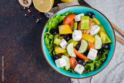 Traditional Greek salad with fresh vegetables, feta cheese and black olives on blue stone table background. Healthy Food Snack Concept. Close up