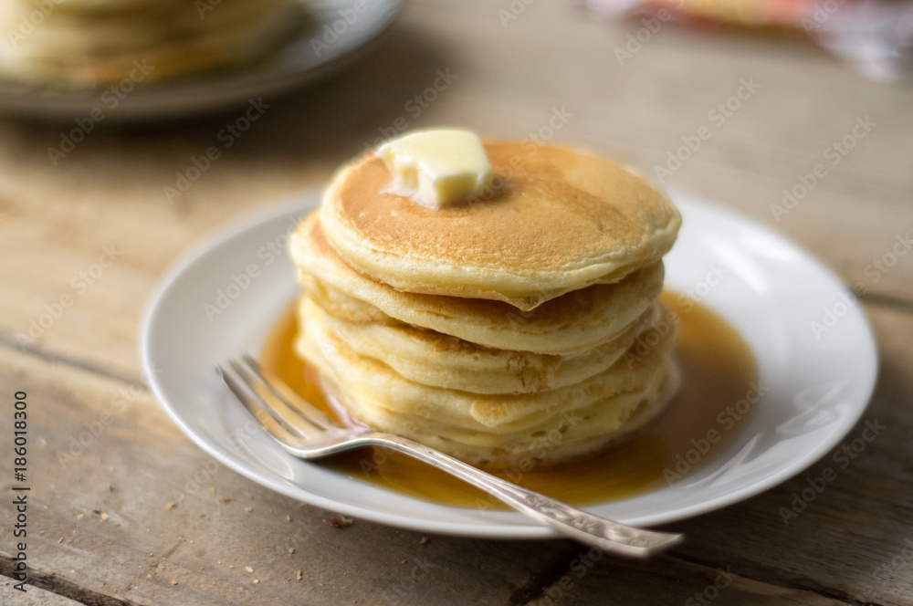 Homemade little pancakes with topping (maple strip and butter) on the plate on the wooden table Homemade little pancakes with topping (maple strip and butter) on the plate on the wooden table