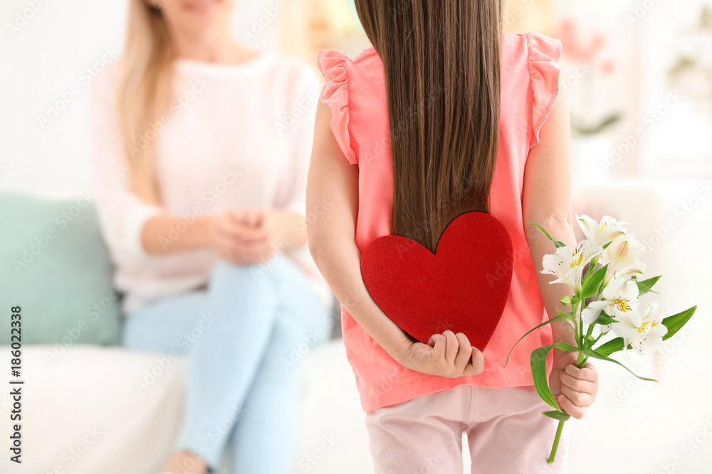 Little girl hiding felt heart and flower for Mother's Day behind her back at home Little girl hiding felt heart and flower for Mother's Day behind her back at home