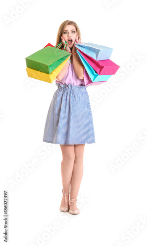 Shocked young woman with shopping bags on white background © Africa Studio
