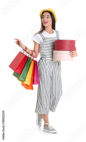 Happy young woman with shopping bags and boxes on white background