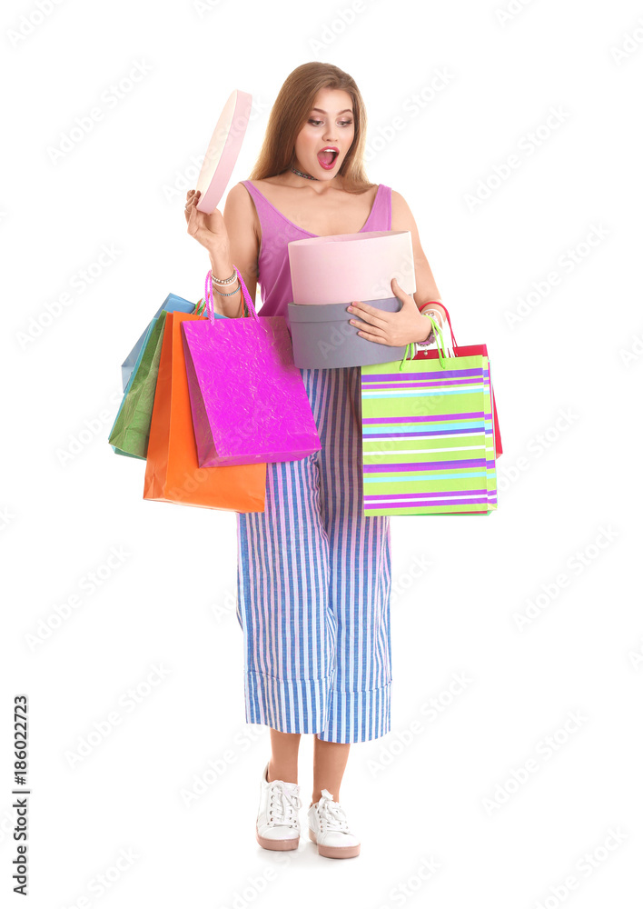 Excited young woman with shopping bags and boxes on white background