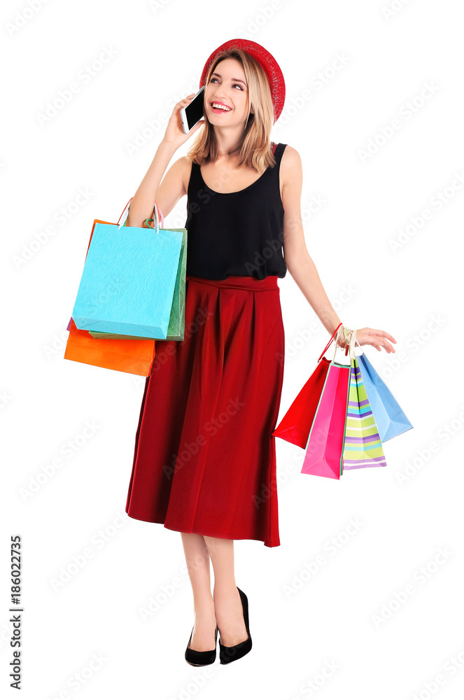 Happy young woman with shopping bags talking on phone against white background Happy young woman with shopping bags talking on phone against white background