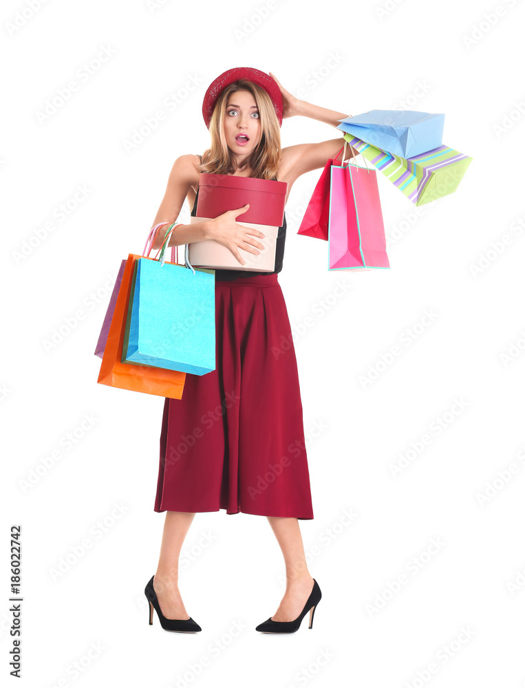 Shocked young woman with shopping bags on white background