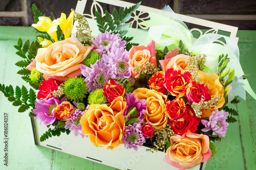 Background wedding or Valentine s Day. Basket bouquet of roses and chrysanthemums on a vintage wooden background.