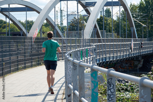 A young man on a morning run on the bridge. Fitness as a lifestyle photo