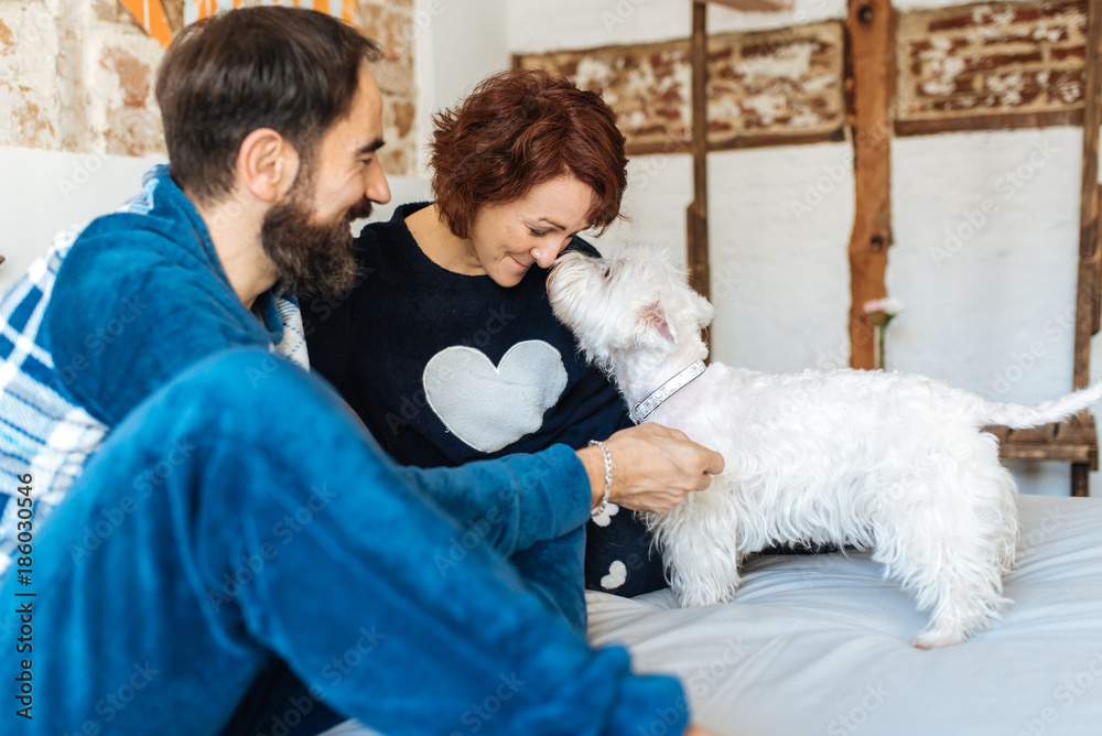 Couple relaxed at home in bed with the dog . Couple relaxed at home in bed with the dog .