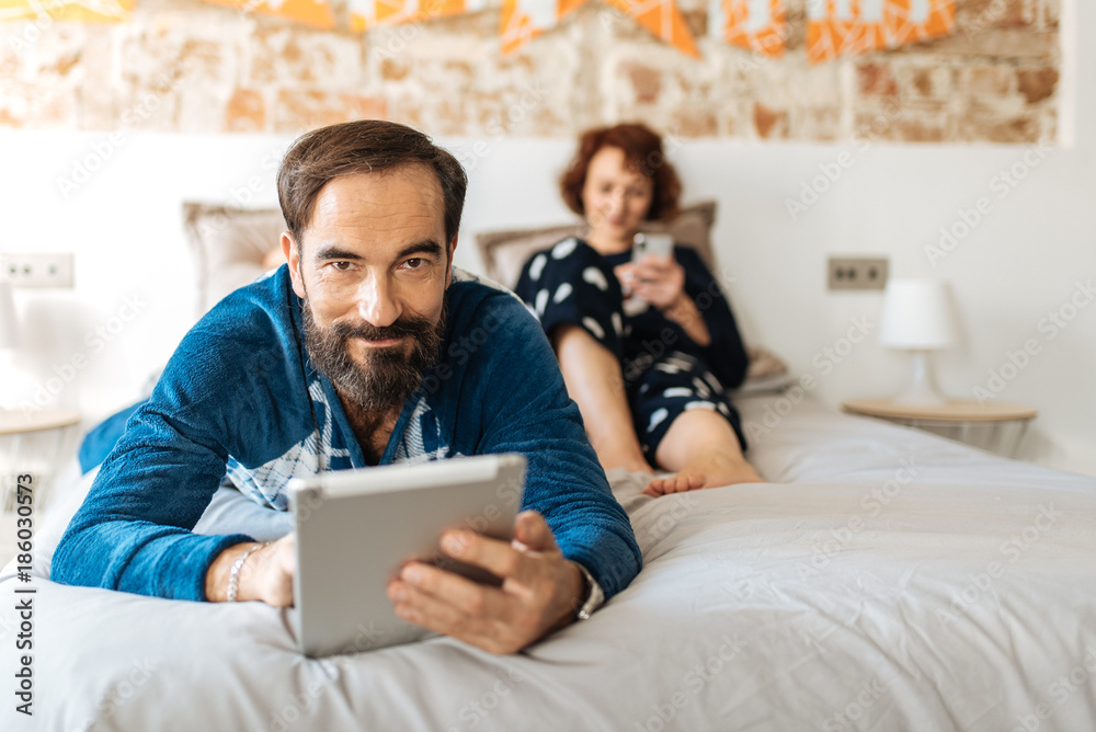 Couple relaxed at home in bed on the mobile phone and tablet.