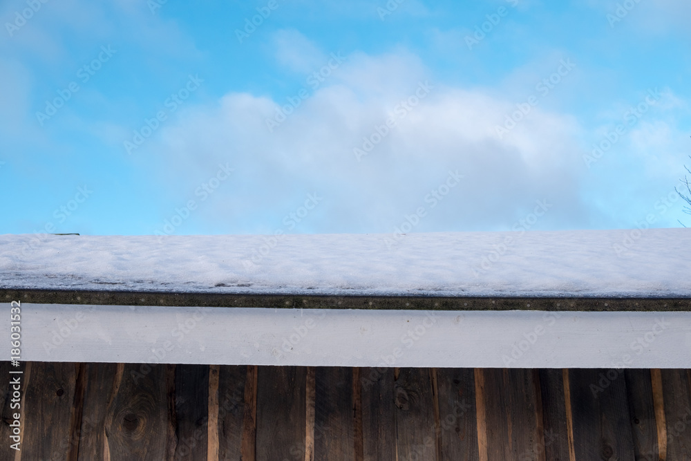Wooden wall, snow on a roof and cloudy sky Wooden wall, snow on a roof and cloudy sky