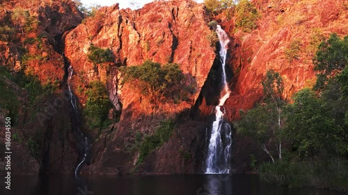 the setting sun turns the cliffs at wangi waterfalls in litchfield national park a brilliant red photo