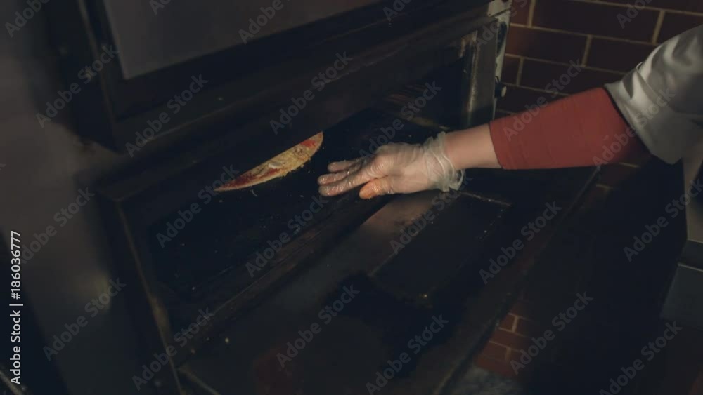 Cooking of pizza. Slow motion.
The pan with pizza is placed in the oven.